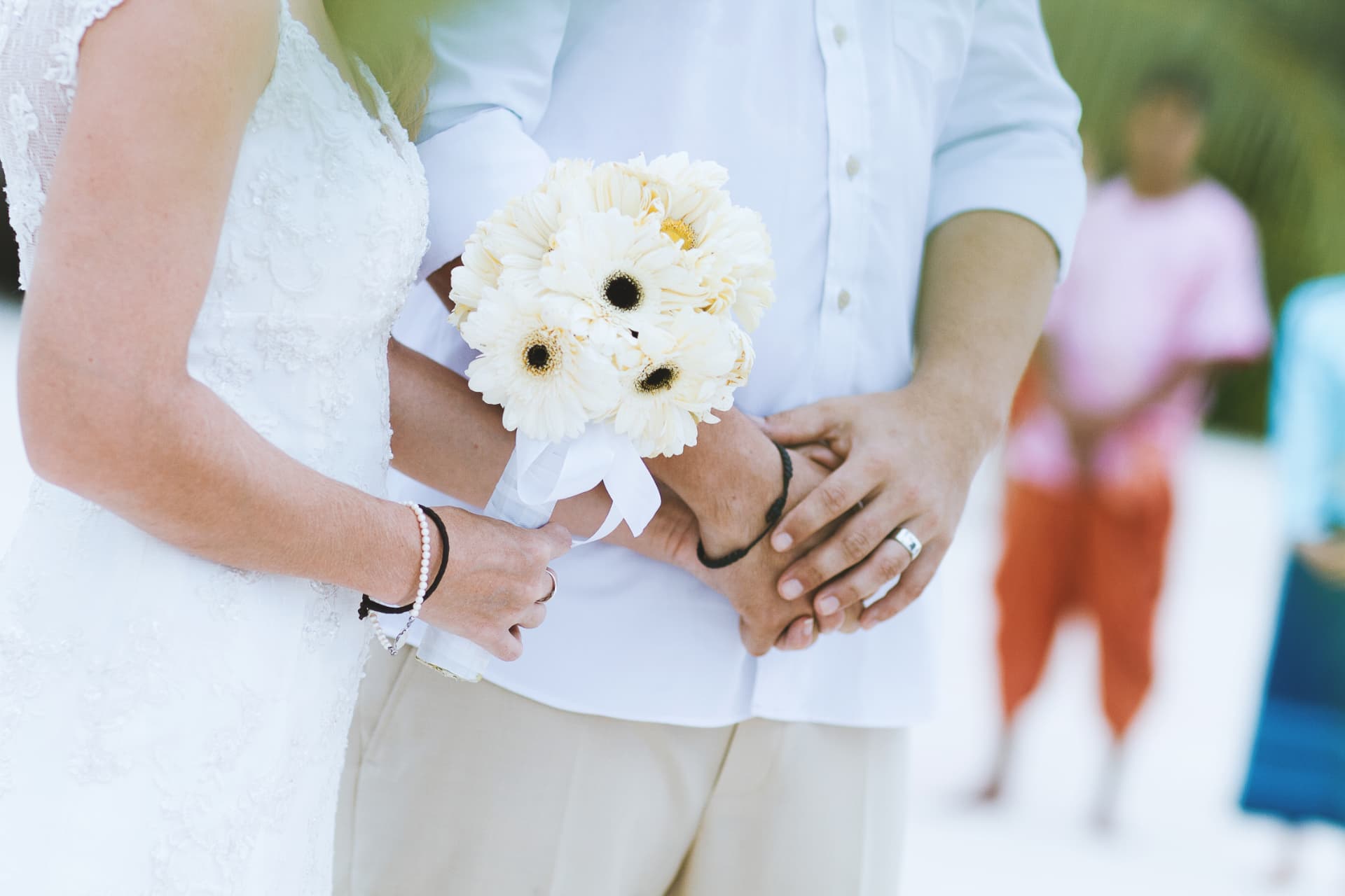 A couple holding hands and carrying white flowers during their ceremony